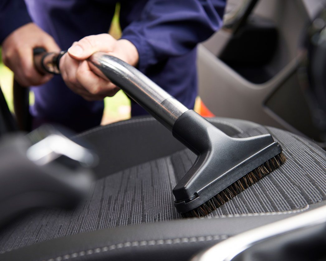 Man Hoovering Seat Of Car During Car Cleaning