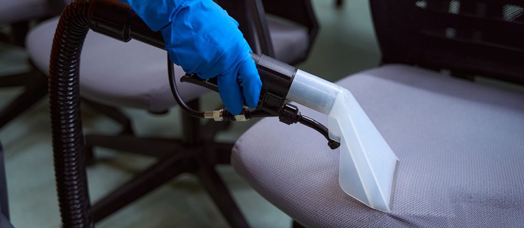 Professional janitor using speacila vacuum-cleaner on chairs
